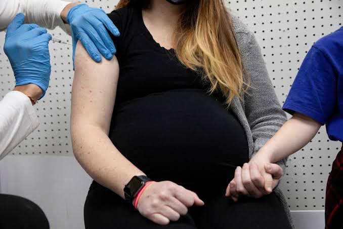 Pregnant woman and medical scan with text overlay: COVID vaccine early pregnancy birth defects